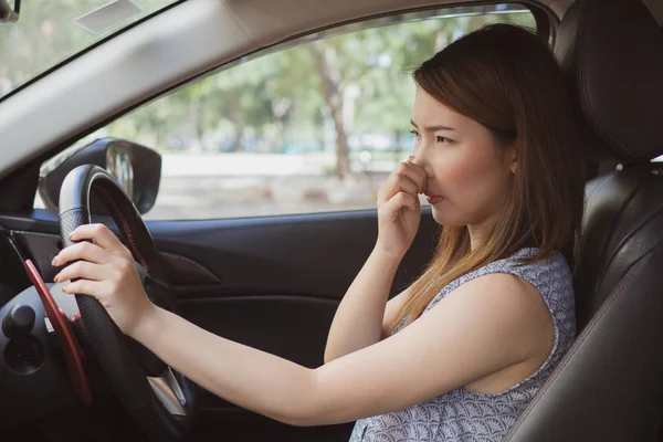 Young woman holding her nose because of bad smell in car