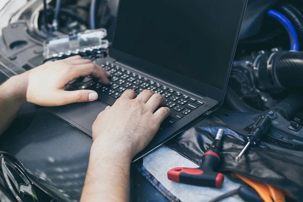 Bir arabayı akort etmek için elektrnotik tanı ekipmanı kullanan mühendis teknisyenini kapat