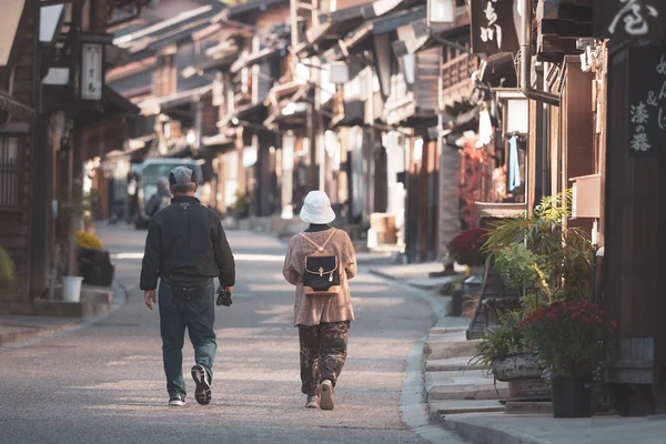Narai-juku 'da, Japonya' da, Nagano, Japonya 'daki eski ahşap evde yürüyen yaşlı çiftin arka görüntüsü..