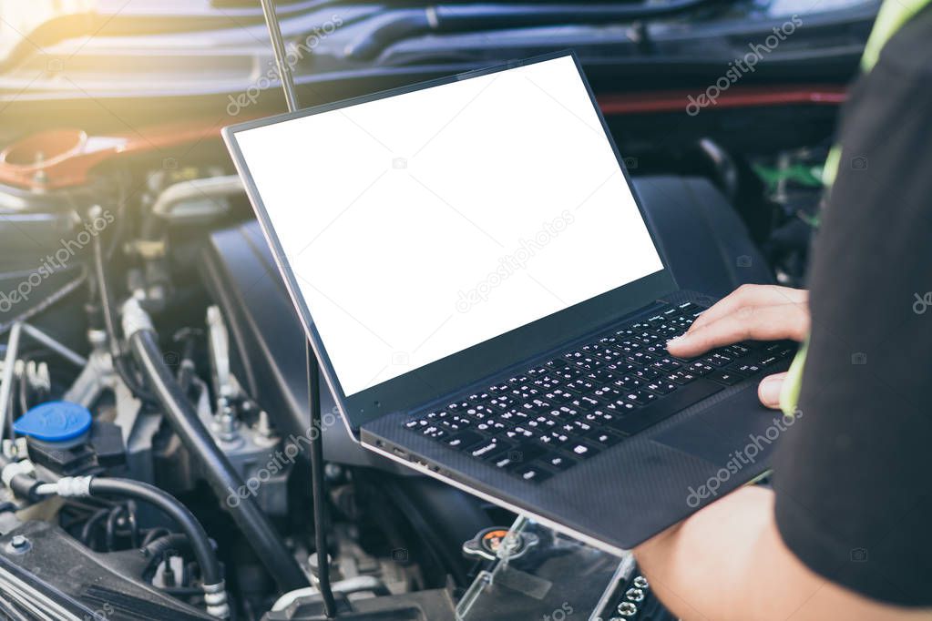 Close up engineer  mechanic using electrnoic diagnostic equipment to tune a car, Laptop blank screen.