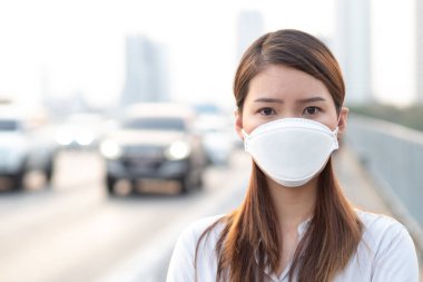 Şehir hava kirliliği kavramı. Şehirdeki PM2.5 hava kirliliğini korumak için N95 maskesi takan kadını kapatın.