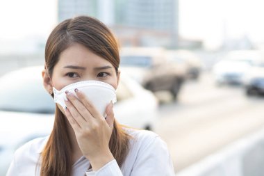 Şehir hava kirliliği kavramı. Şehirdeki PM2.5 hava kirliliğini korumak için N95 maskesi takan kadını kapatın.