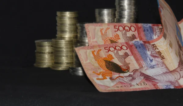 Koyu renkli bir arka plandaki sikkeler. Sikkekazakistan tenge ve rus rouble karanlık bir arka plan üzerinde. Kazak parası. Tenge sikkeleri. sikke ve tenge kağıt banknotlar büyük kazık