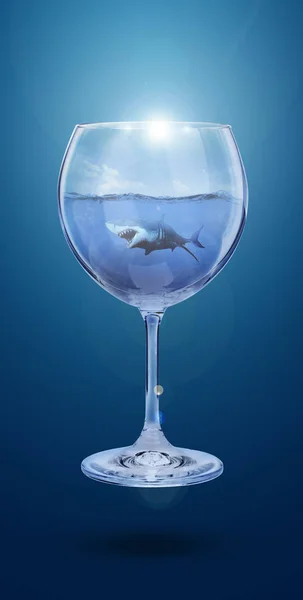 Şarap bardağı mavi arka plan üzerinde izole. Mavi arka planda bir kadeh şarapta köpekbalığıyla okyanus kolajı. Alkolün zararı. Deniz suyu ile şarap bardağı. Zehirli su