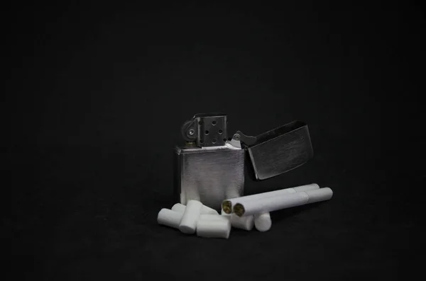 Metal bir çakmak, sigara ve sigara filtrelerinin koyu arkaplanda bileşimi.