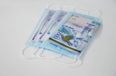 Notların kompozisyonu, Kazakistan madeni paraları ve siyah bir arka planda tıbbi maske. Kazak parası ve tıbbi maske..