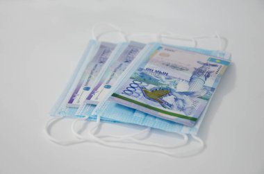 Notların kompozisyonu, Kazakistan madeni paraları ve siyah bir arka planda tıbbi maske. Kazak parası ve tıbbi maske..