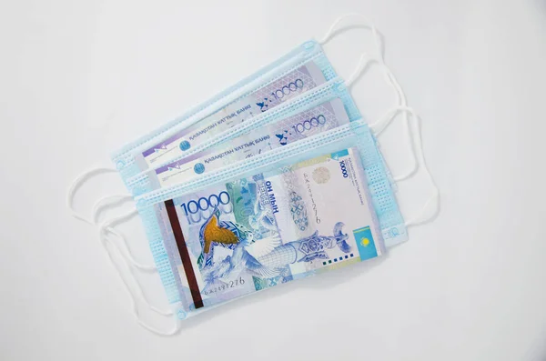 Notların kompozisyonu, Kazakistan madeni paraları ve siyah bir arka planda tıbbi maske. Kazak parası ve tıbbi maske..