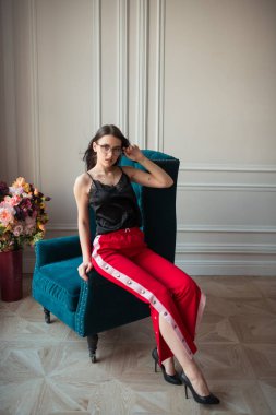 kapalı koltuk üzerinde poz kırmızı gözlük şık genç kadın pantolon