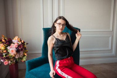 kapalı koltuk üzerinde poz kırmızı gözlük şık genç kadın pantolon