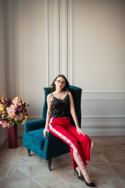 kapalı koltuk üzerinde poz kırmızı gözlük şık genç kadın pantolon