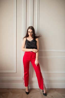 Genç şehvetli kadın kapalı beyaz duvara poz gözlük