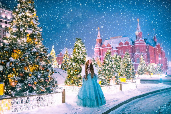 Young girl in carnival dress and hat posing in winter New Year fairy tale environment