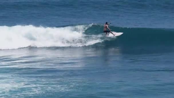 En surfare rider en våg i bränningen på ocean blue i surf plats. — Stockvideo