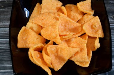 Üçgen şeklinde kesilmiş tortilla cipsi, mısır tortillası ve geleneksel baharatlı ketçap, tuz, tatlı biber, kraker karışımı, çeşitli atıştırmalıklar.