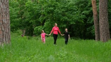 Anne ve çocuklar ormanda yürürler. Aile sporları doğada.