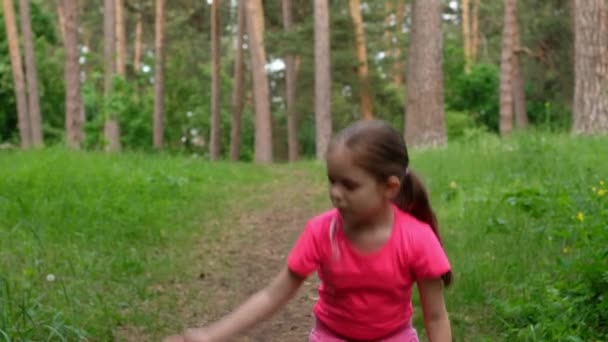 Menina mostrando seus músculos e sorrindo. A criança envolve-se na aptidão na natureza . — Vídeo de Stock