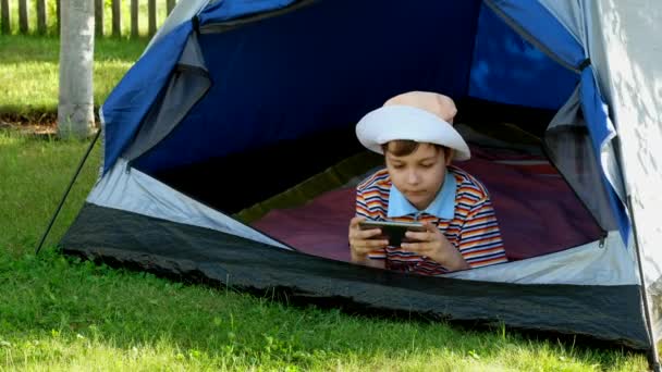 Mały Chłopiec Kapeluszu Gra Gry Online Swoim Telefonie Siedząc Namiocie — Wideo stockowe