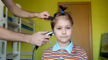 Berber dükkanındaki güzel çocuk. Baba, küçük oğlunun saçını kırpıcı ile kesiyor. Coronavirus, karantina, covid19.