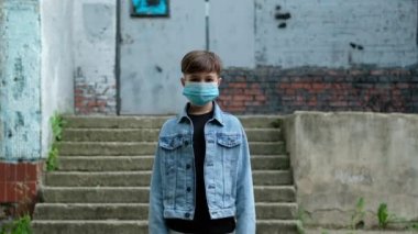 Küçük çocuk dışarıda tıbbi maskesini çıkarıyor. Karantinaya son verecek çocuk, koronavirüs, kovid19, kendini izole etme..