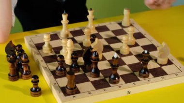 Çocuk ve baba evde birlikte vakit geçirirken satranç oynuyorlar. Baba ve oğul masada masa oyunu oynuyorlar..