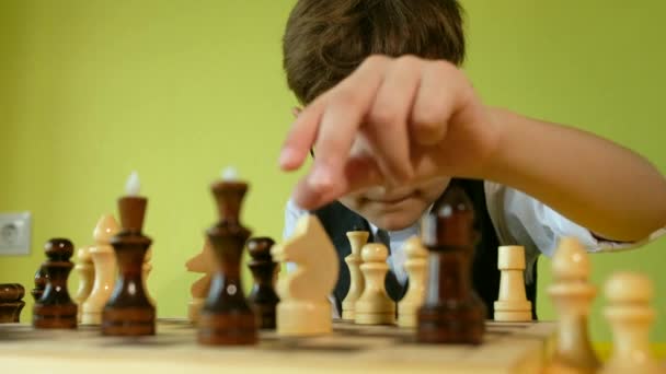 Kind schaken aan tafel. Kleine jongen met bril ontwikkelen schaakstrategie, bordspel spelen met vriend. — Stockvideo