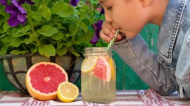 Çocuk açık havada taze limonata içiyor..