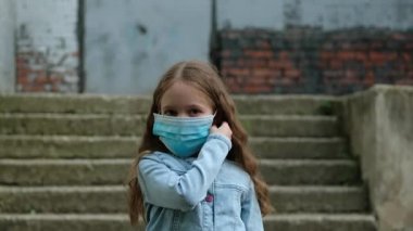 Küçük kız dışarıda tıbbi maskesini çıkarıyor. Karantinaya son verecek çocuk, koronavirüs, kovid19, kendini izole etme..