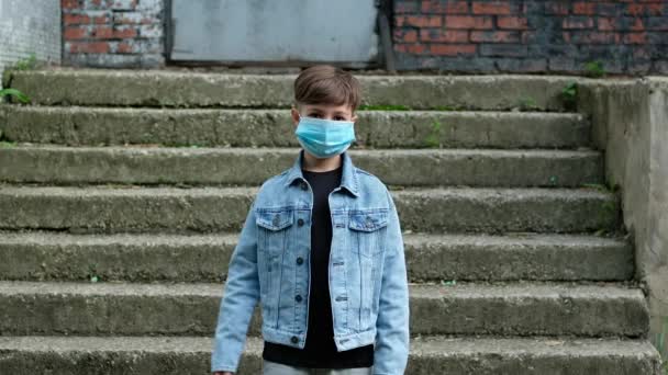 Den lille pojken tar av sig sin mask utomhus. Barn som avslutar karantänen, coronavirus, covid19, isolering. — Stockvideo