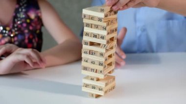 Çocuklar evdeki masada tahta bir masa oyunu oynuyorlar..