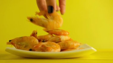 Kız, sarı arka planda kaynamış karides ya da karides empoze eder.