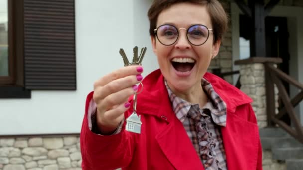 Hermosa mujer con gafas sostiene las llaves de la casa nueva. La dama de negocios está feliz de comprar un apartamento. — Vídeos de Stock