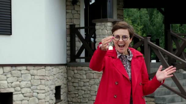 Hermosa mujer con gafas sostiene las llaves de la casa nueva. La dama de negocios está feliz de comprar un apartamento. — Vídeos de Stock