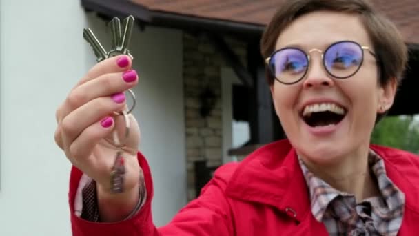 Όμορφη γυναίκα με γυαλιά κρατά τα κλειδιά από το νέο σπίτι. Επιχειρηματίας κυρία είναι ευτυχής να αγοράσει ένα διαμέρισμα. — Αρχείο Βίντεο