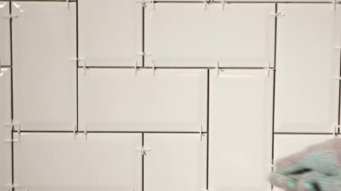 Mutfaktaki duvarda ringa kemiği desenli beyaz seramik fayanslar döşeyen.