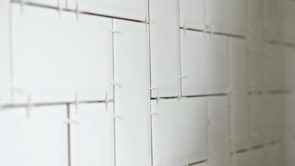 Werken tiler leggen witte keramische tegels in een visgraat patroon op de muur in de keuken. — Stockvideo