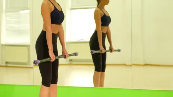 Αθλητική γυναίκα στα αθλητικά κάνει ασκήσεις με bodybar στο γυμναστήριο. — Αρχείο Βίντεο