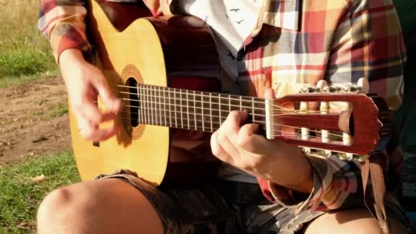Ręce człowieka, który gra na gitarze podczas letniego pikniku na łonie natury. — Wideo stockowe