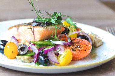 Limonlu ızgara somon bifteği, salata ve domates.