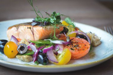 Taze somon bifteği ve beyaz tabakta sebze.