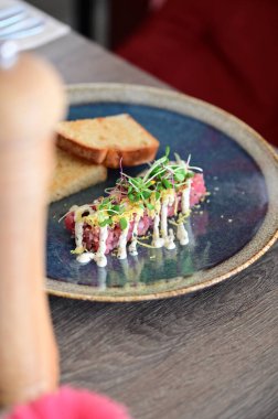 Kızarmış ekmek ve kırsal bir tabakta mikro yeşilliklerle servis edilen, bir restoran ortamında ahşap bir masada sunulan, Avrupa mutfağını ön plana çıkaran,.