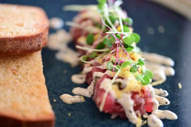 Kızarmış ekmek ve kırsal bir tabakta mikro yeşilliklerle servis edilen, bir restoran ortamında ahşap bir masada sunulan, Avrupa mutfağını ön plana çıkaran,.