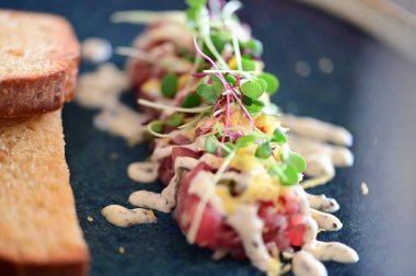 Kızarmış ekmek ve kırsal bir tabakta mikro yeşilliklerle servis edilen, bir restoran ortamında ahşap bir masada sunulan, Avrupa mutfağını ön plana çıkaran,.