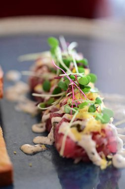 Kızarmış ekmek ve kırsal bir tabakta mikro yeşilliklerle servis edilen, bir restoran ortamında ahşap bir masada sunulan, Avrupa mutfağını ön plana çıkaran,.