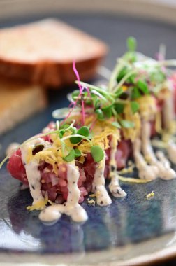 Kızarmış ekmek ve kırsal bir tabakta mikro yeşilliklerle servis edilen, bir restoran ortamında ahşap bir masada sunulan, Avrupa mutfağını ön plana çıkaran,.