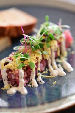 Kızarmış ekmek ve kırsal bir tabakta mikro yeşilliklerle servis edilen, bir restoran ortamında ahşap bir masada sunulan, Avrupa mutfağını ön plana çıkaran,.