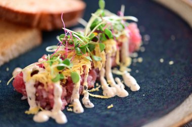 Kızarmış ekmek ve kırsal bir tabakta mikro yeşilliklerle servis edilen, bir restoran ortamında ahşap bir masada sunulan, Avrupa mutfağını ön plana çıkaran,.