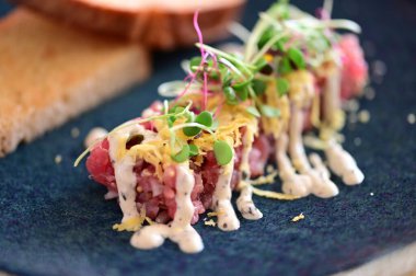 Kızarmış ekmek ve kırsal bir tabakta mikro yeşilliklerle servis edilen, bir restoran ortamında ahşap bir masada sunulan, Avrupa mutfağını ön plana çıkaran,.