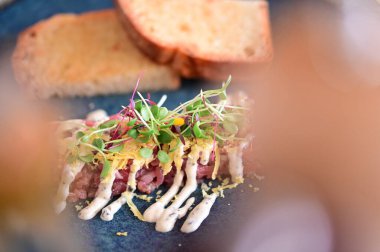 Kızarmış ekmek ve kırsal bir tabakta mikro yeşilliklerle servis edilen, bir restoran ortamında ahşap bir masada sunulan, Avrupa mutfağını ön plana çıkaran,.