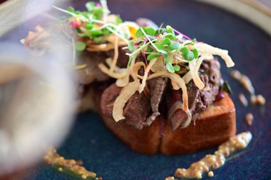 Tavuklu ciğer, karamelli soğan ve mikroyeşillik ile kaplanmış yakın plan kızarmış ekmek, Avrupa mutfağı tarzında servis edilir..